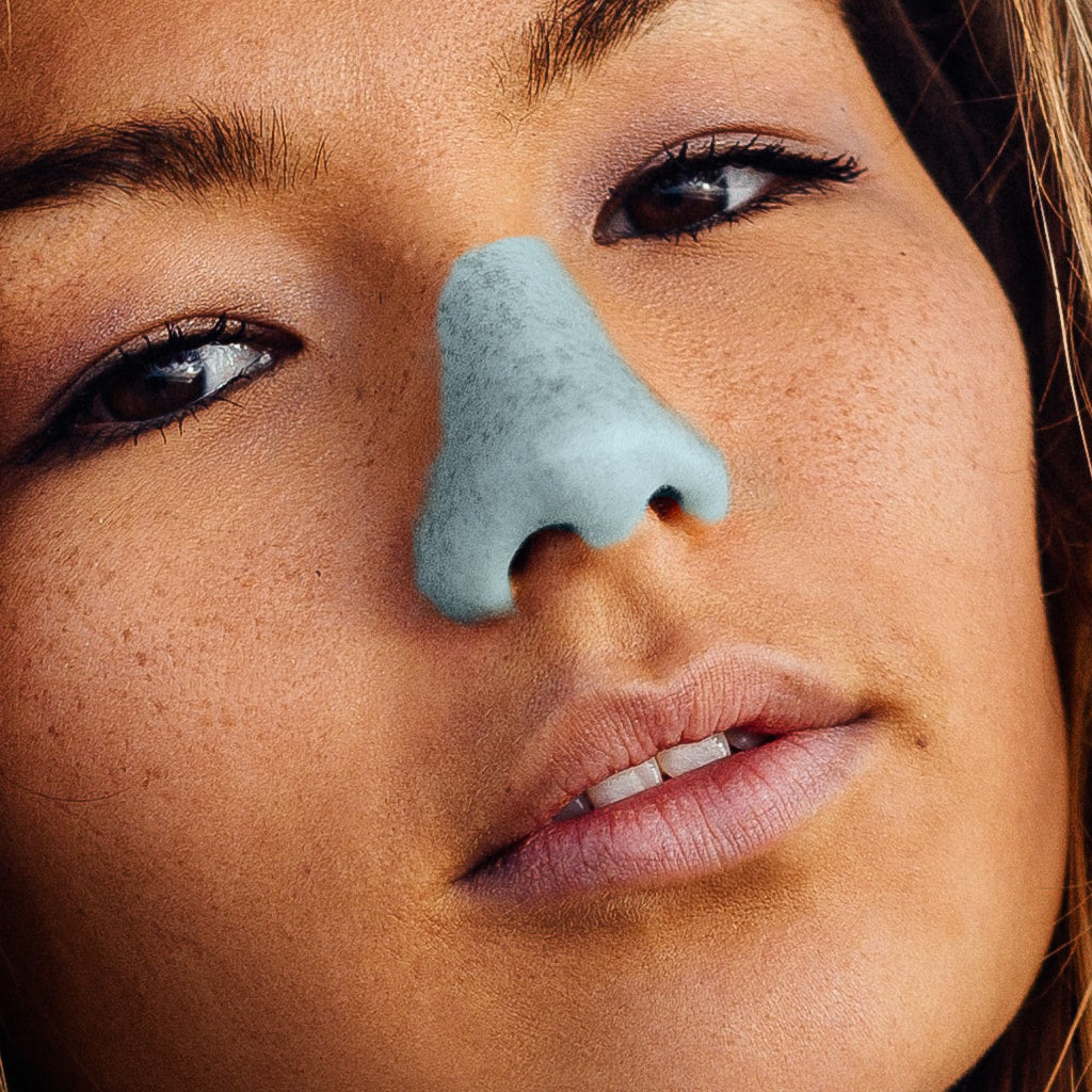 Close up of women's face wearing blue Nöz sunscreen on her nose